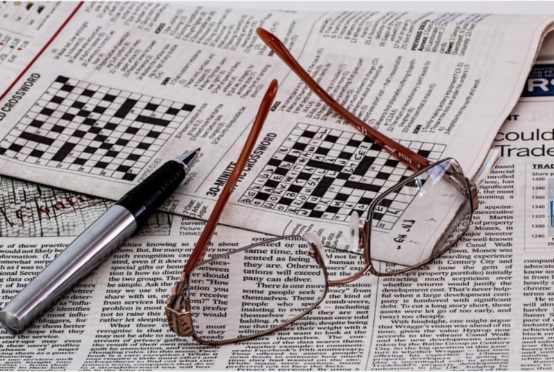 glasses and a pen lying on top of a crossword puzzle