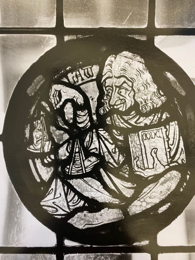 Stained glass art from the window of Grace Dodge Cafeteria depicting a figure holding a codex and the scales of justice
