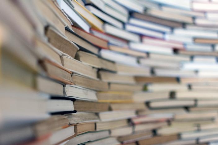 A wall of books stacked on top of each other with paper edges sticking out