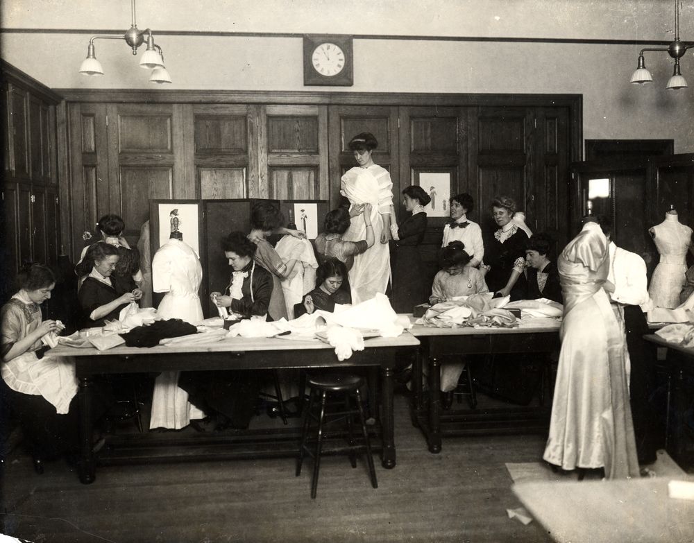 Dodge Hall. Dressmaking class. Clothing Laboratory, 3rd floor. Professor Jane Fales, in white shirt waist, black tie, standing at right rear.