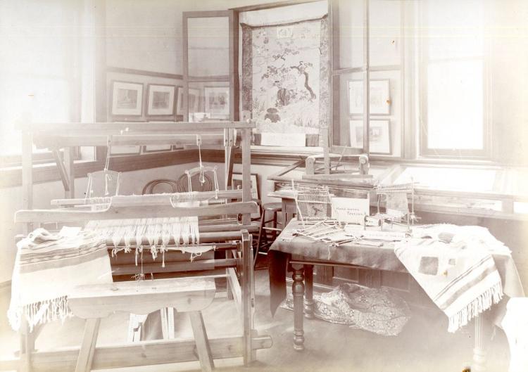 Black and white photograph depicting tapestries in looms and other textiles from around the world.