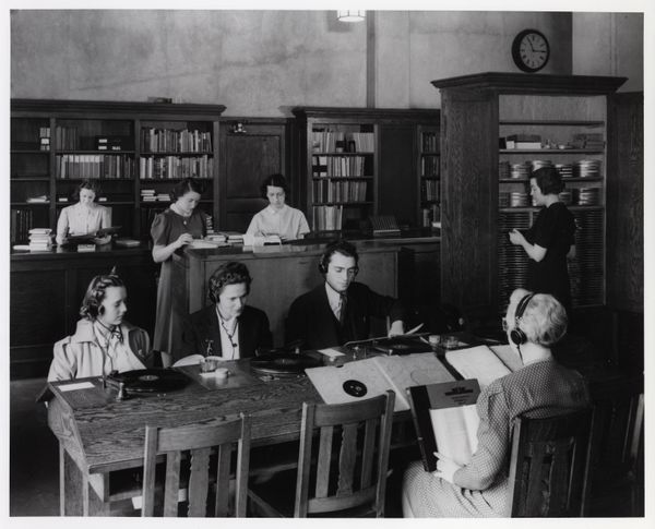 Black and white photo from 1940 of students sitting at a listening table, each wearing headphones.